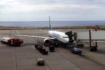 Ein Flieger an der Gangway der gerade betankt wird, das Gepäck der Reisenden steht zum einladen neben dem Flugzeug der Fluggesellschaft bereit.